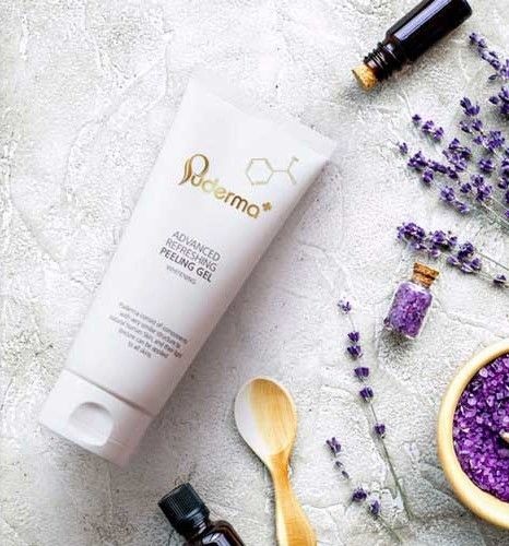 Skincare product with lavender flowers and essential oils on a textured surface.